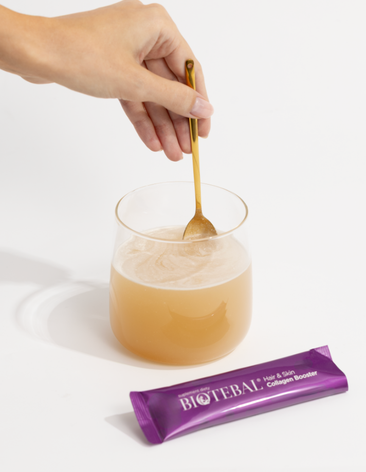 ręka mieszająca rozpuszczany w szklance Biotebal Hair & Skin Collagen Booster