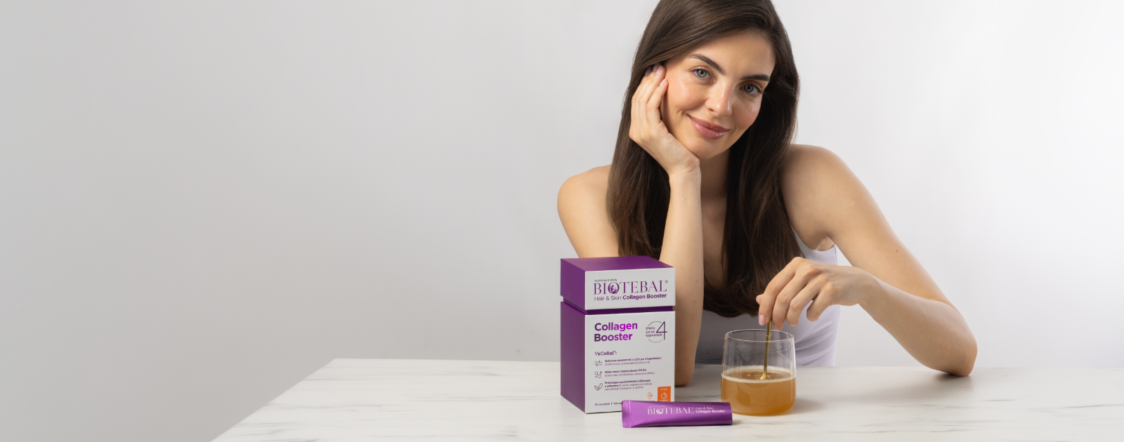 Uśmiechnięta kobieta z produktem Biotebal Collagen Skin & Hair